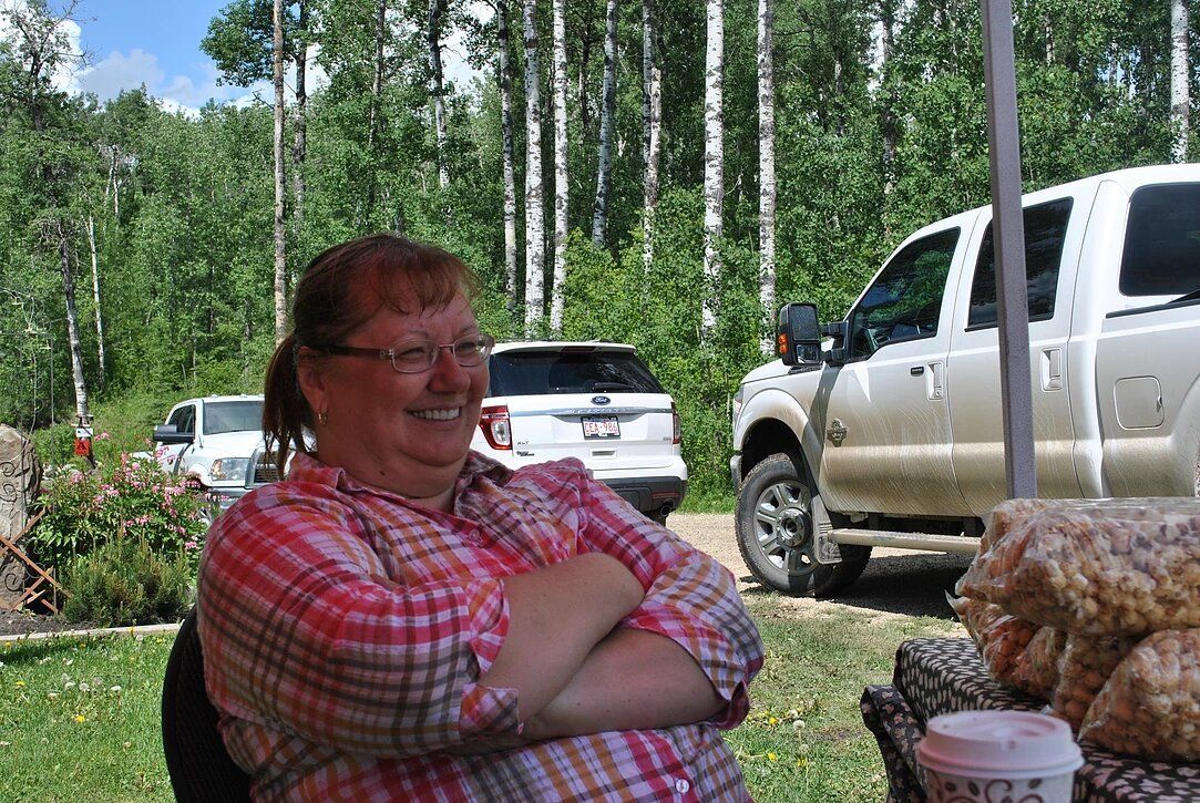 A woman is sitting in front of a truck with her arms crossed.