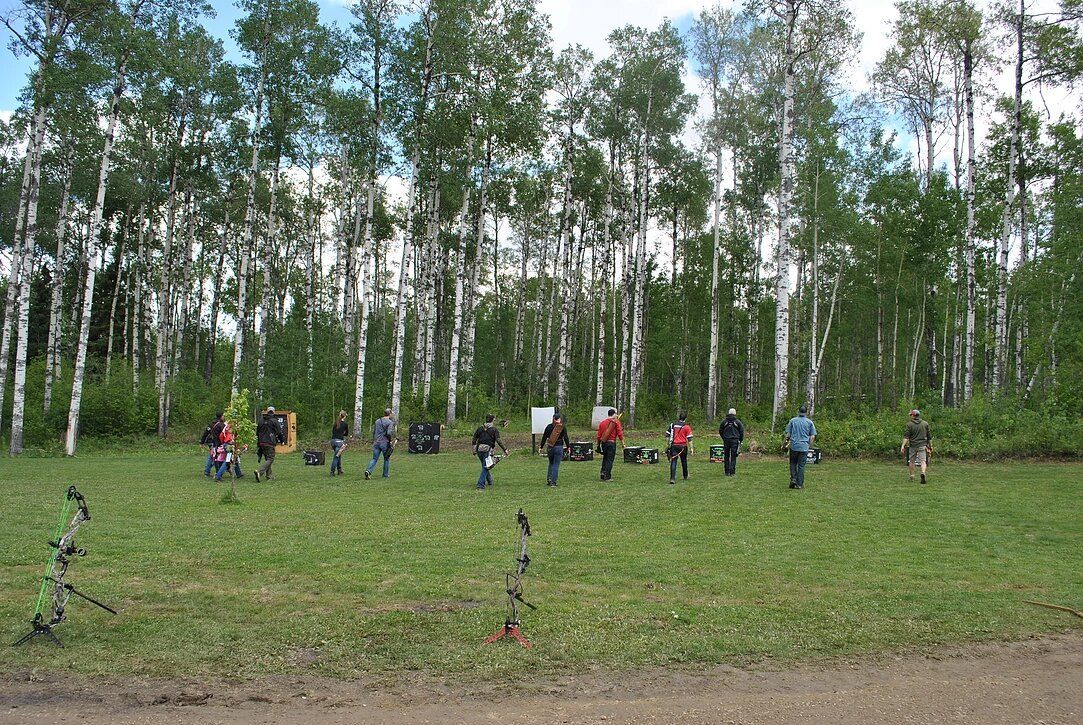 A group of people are standing in a field with trees in the background.
