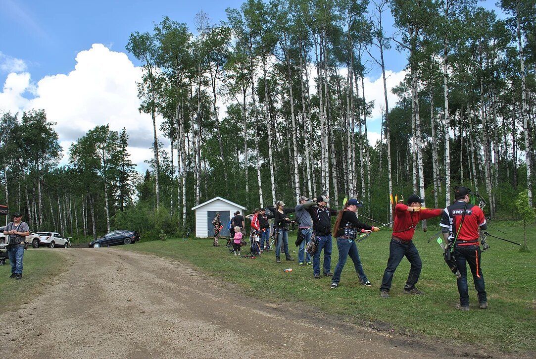 A group of people are standing in a field with trees in the background