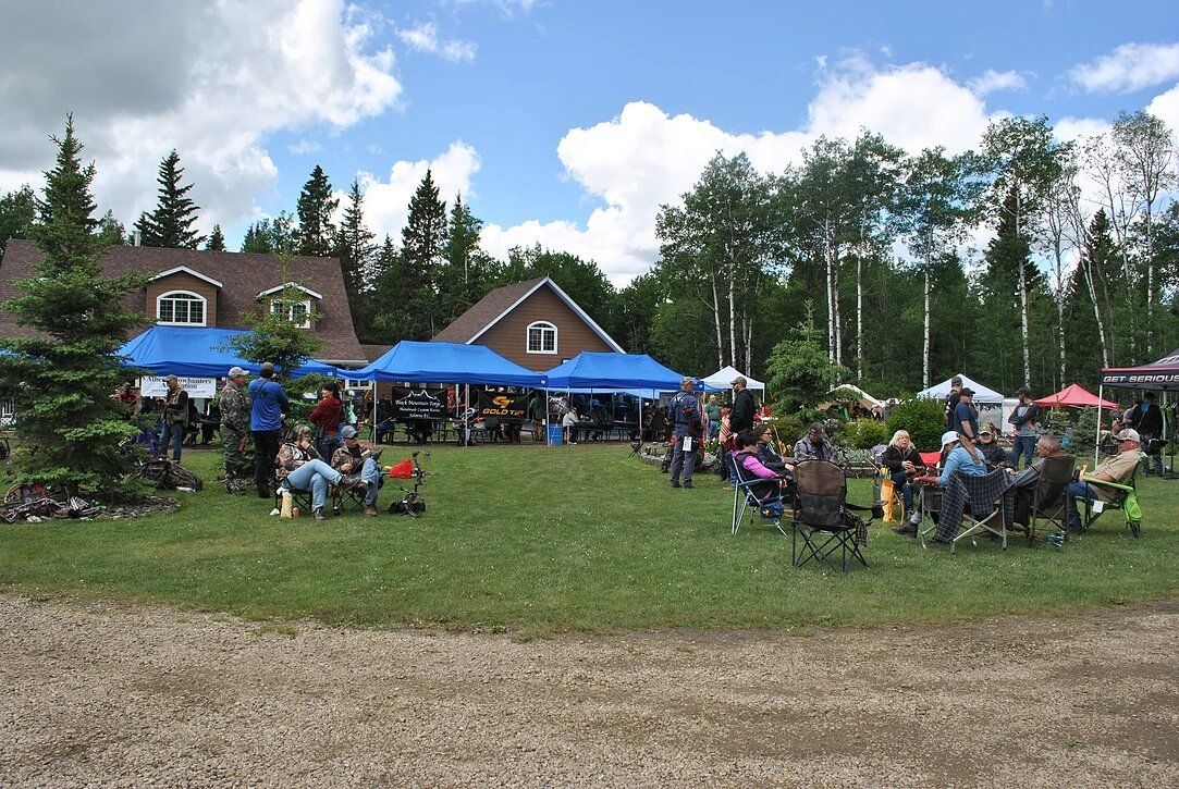 A group of people are sitting under blue tents in a field.