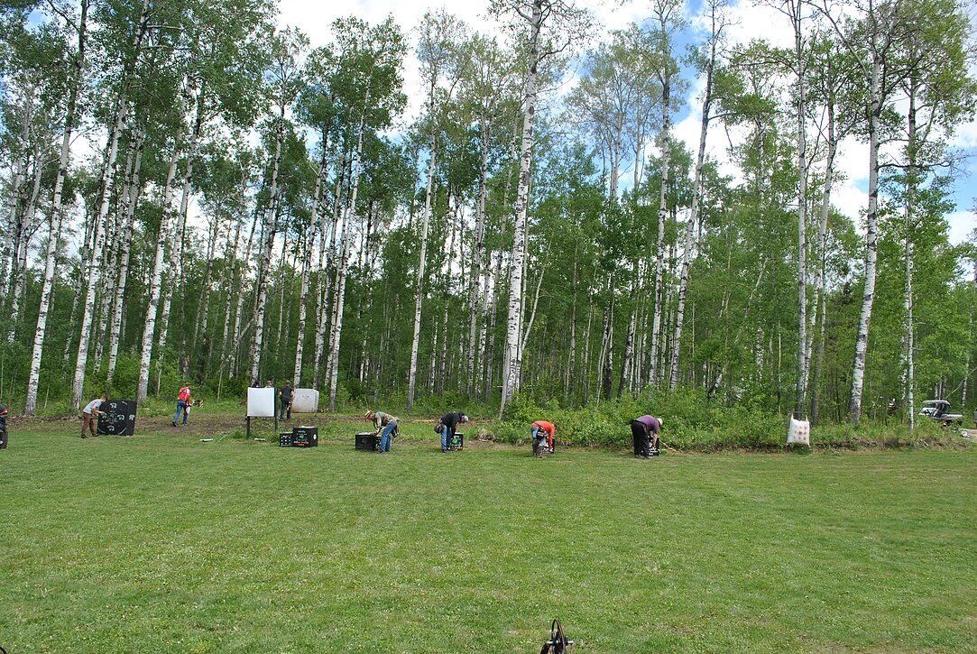 A group of people are standing in a field with trees in the background.