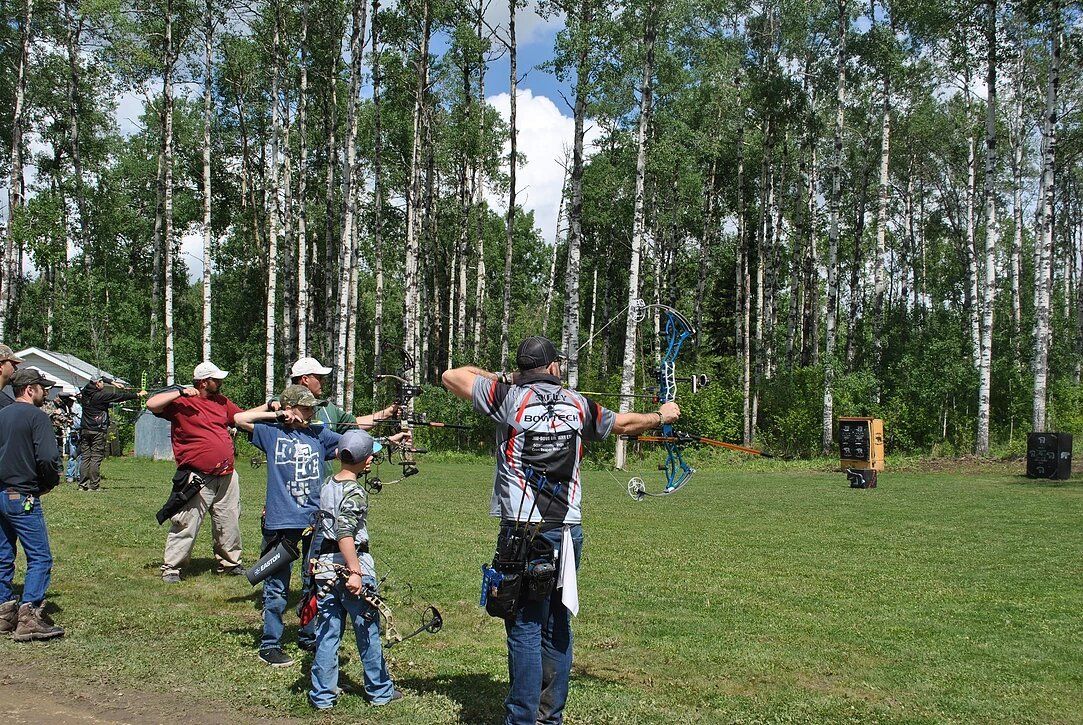 A group of people are standing in a field holding bows and arrows.