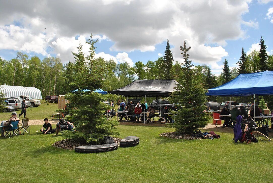 A group of people are sitting under tents in a field.