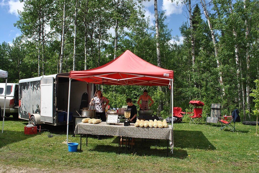 A group of people are standing under a red tent in a field.