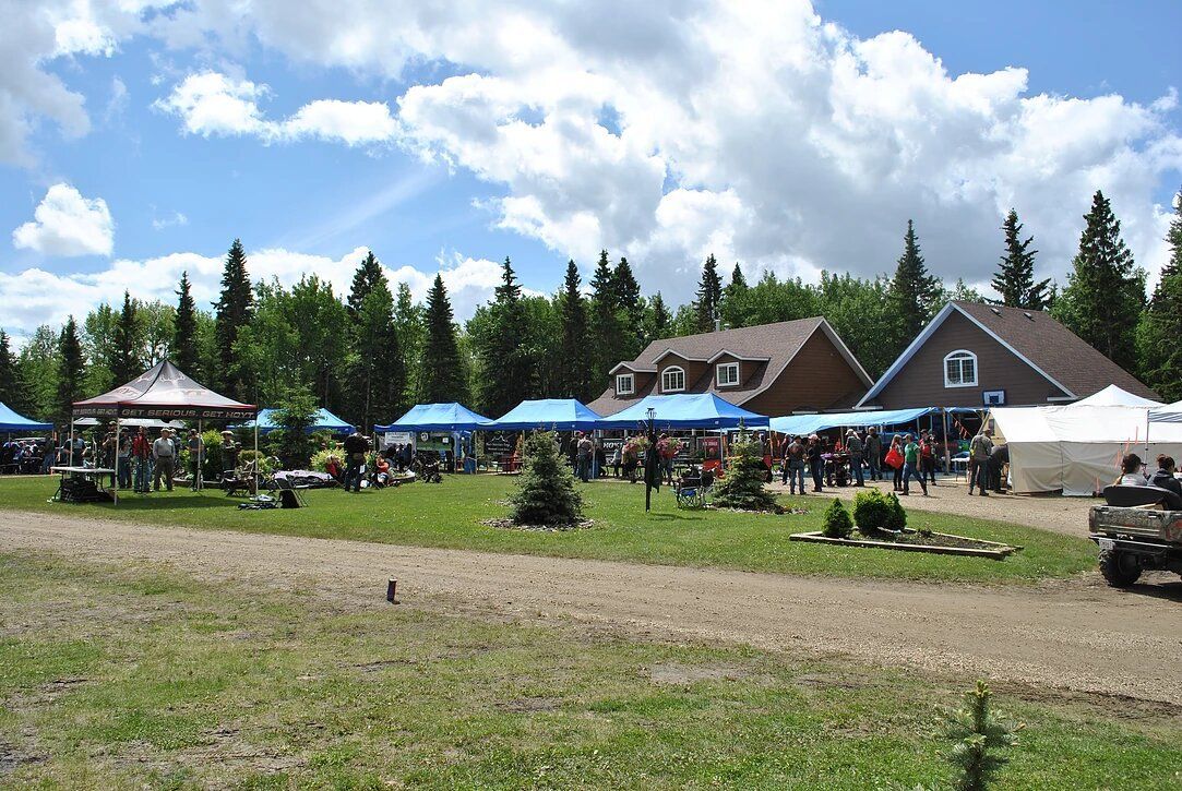 A group of people are gathered in a field in front of a house.
