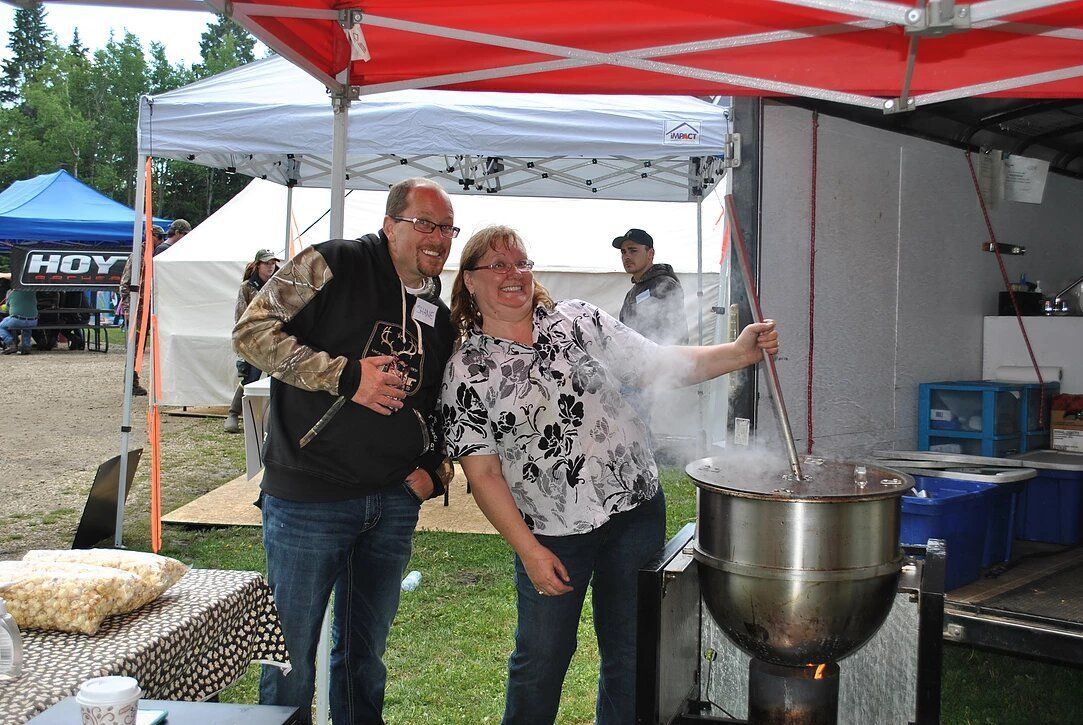A man and a woman are standing in front of a large pot.