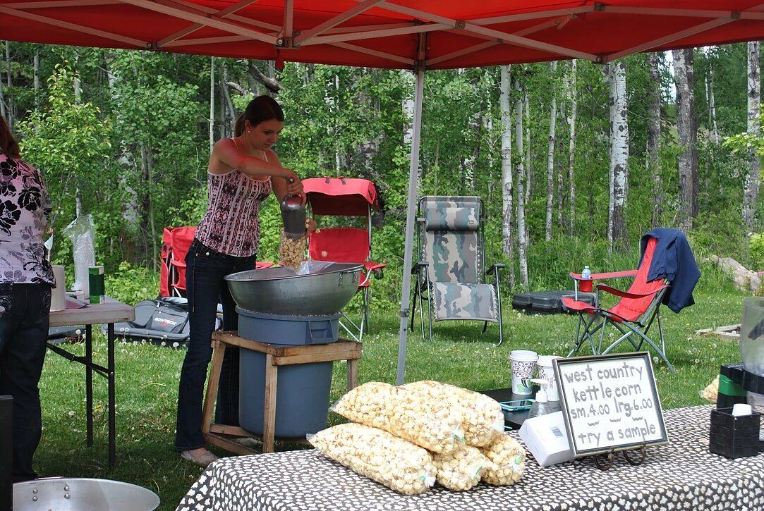A woman is making popcorn under a tent in the woods.