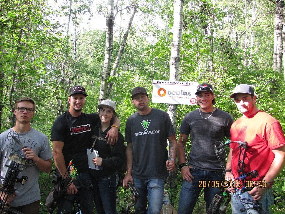 A group of people are posing for a picture in the woods.
