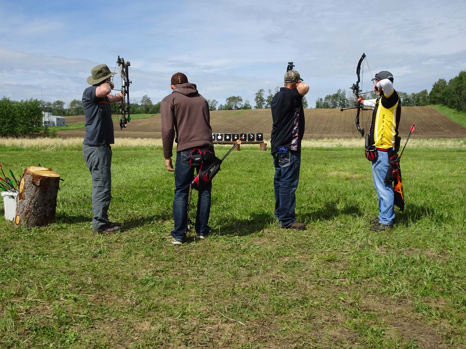 A group of men are standing in a field holding bows and arrows.