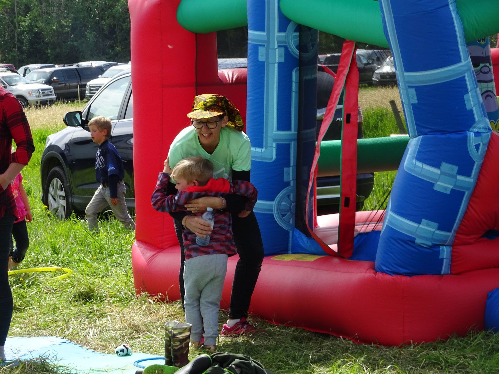 A man is holding a child in front of a bouncy house.
