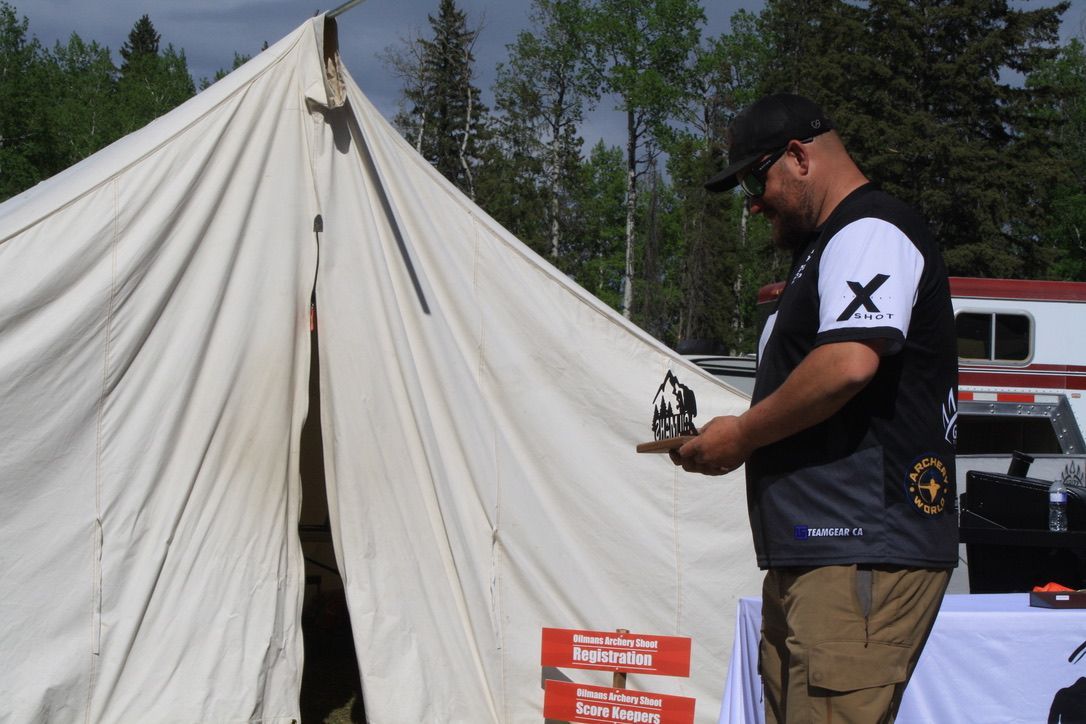 A man standing in front of a tent with the letter x on his shirt