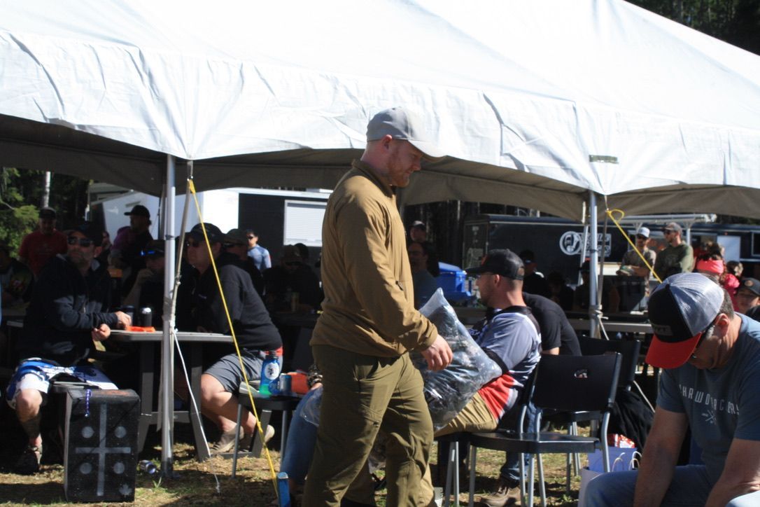 A man is walking in front of a group of people under a tent.