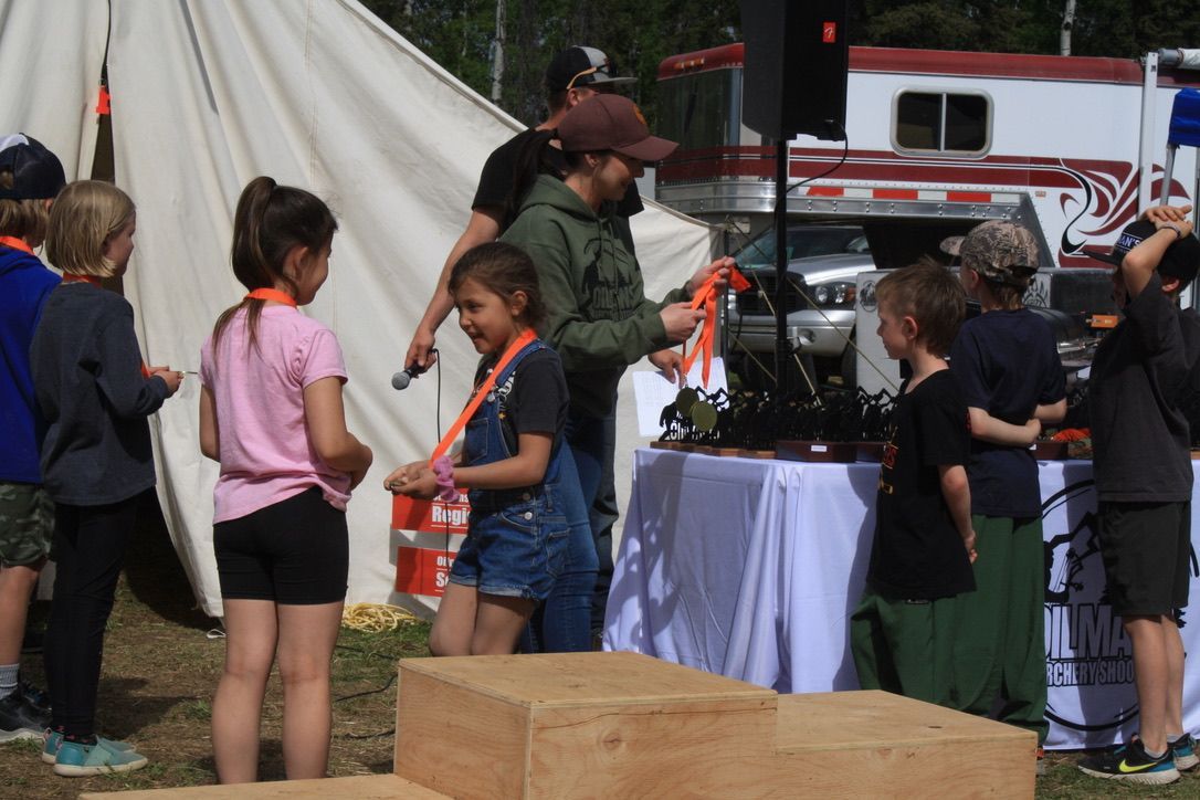 A group of children are standing around a table in front of a fire truck.