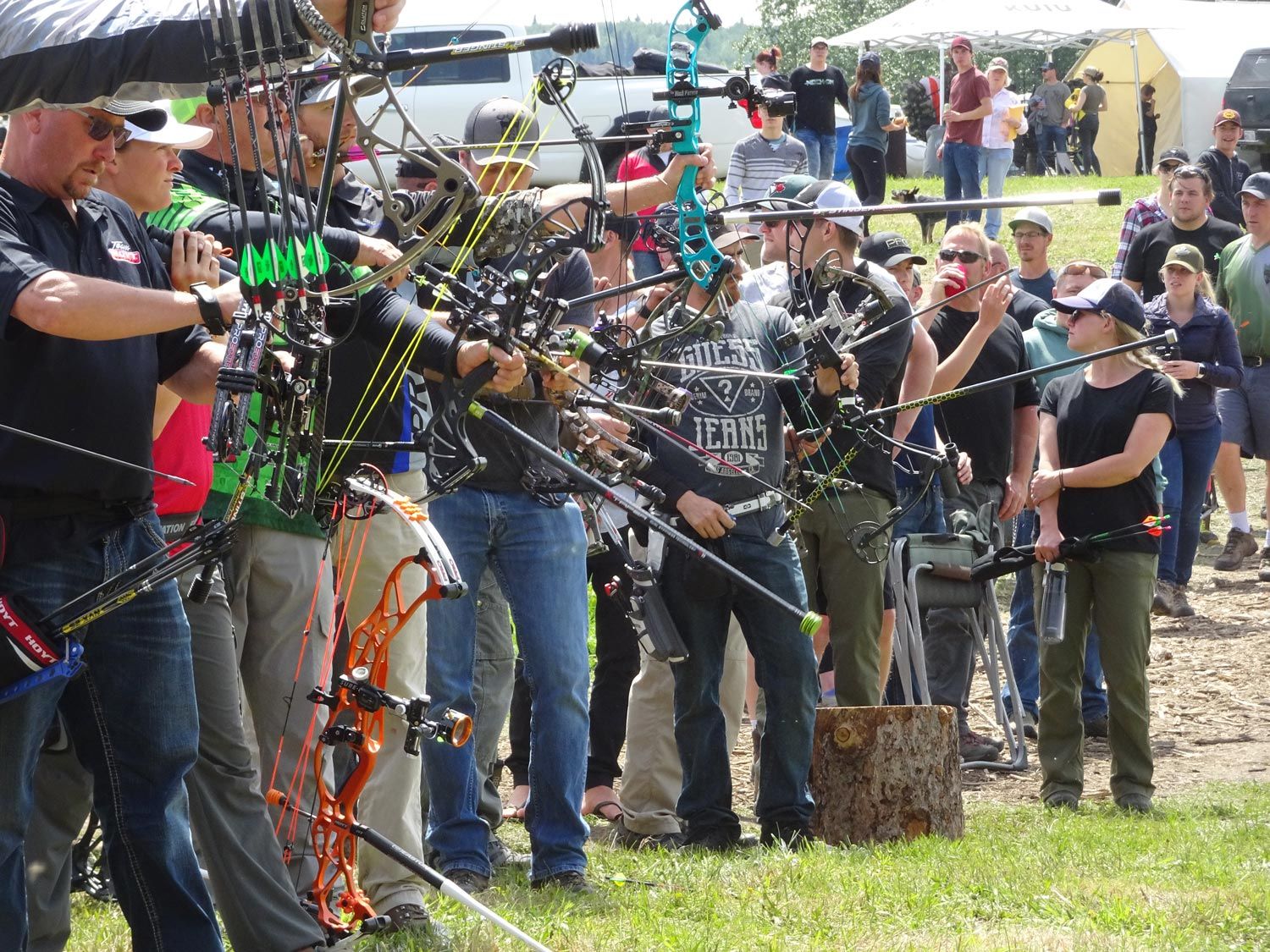 A group of people are standing in a field holding bows and arrows.