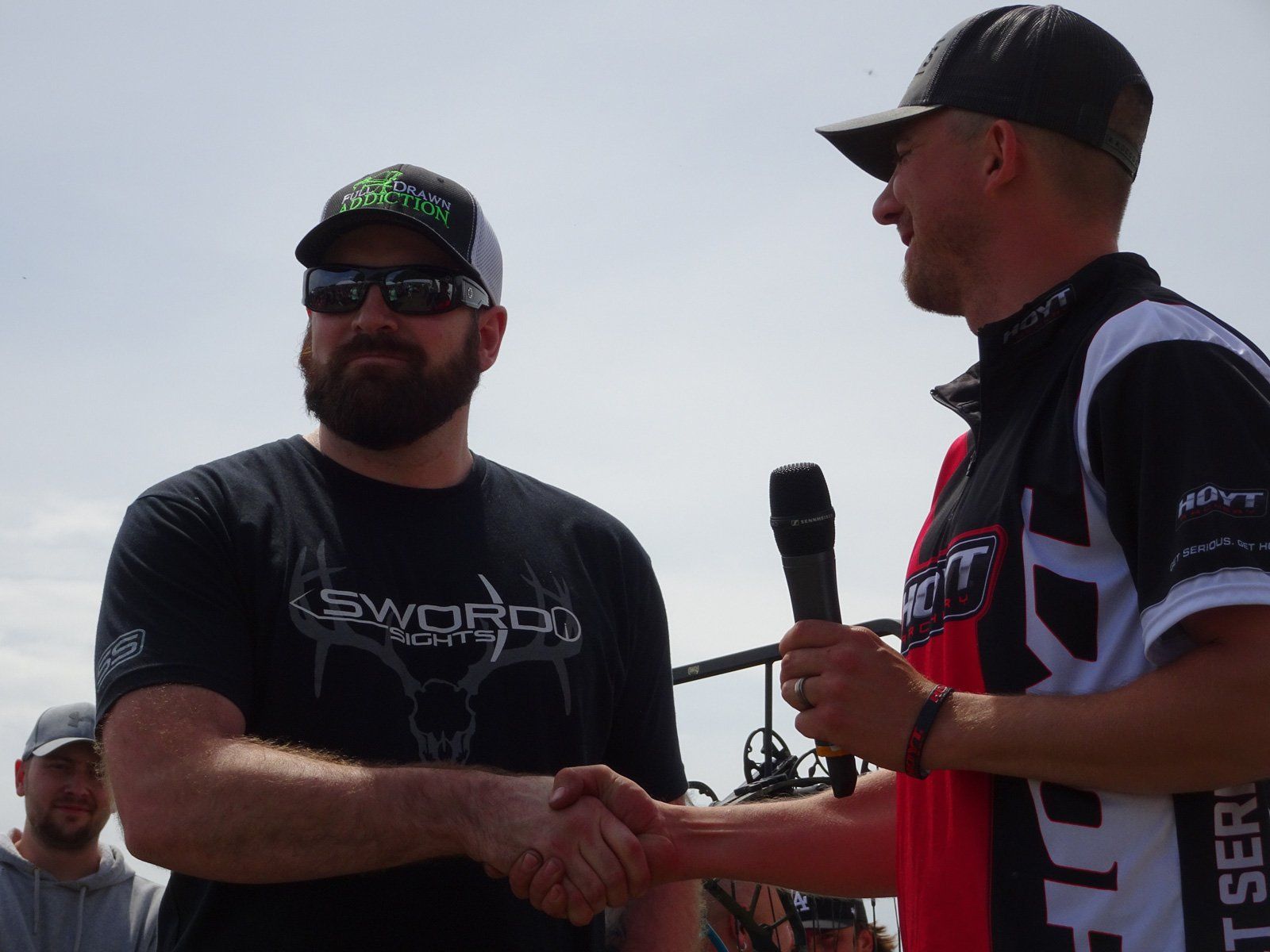 A man with a beard is shaking hands with another man