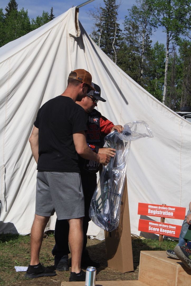 A couple of men standing in front of a tent with a sign that says 