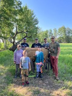 A group of people are standing next to a deer in a field.