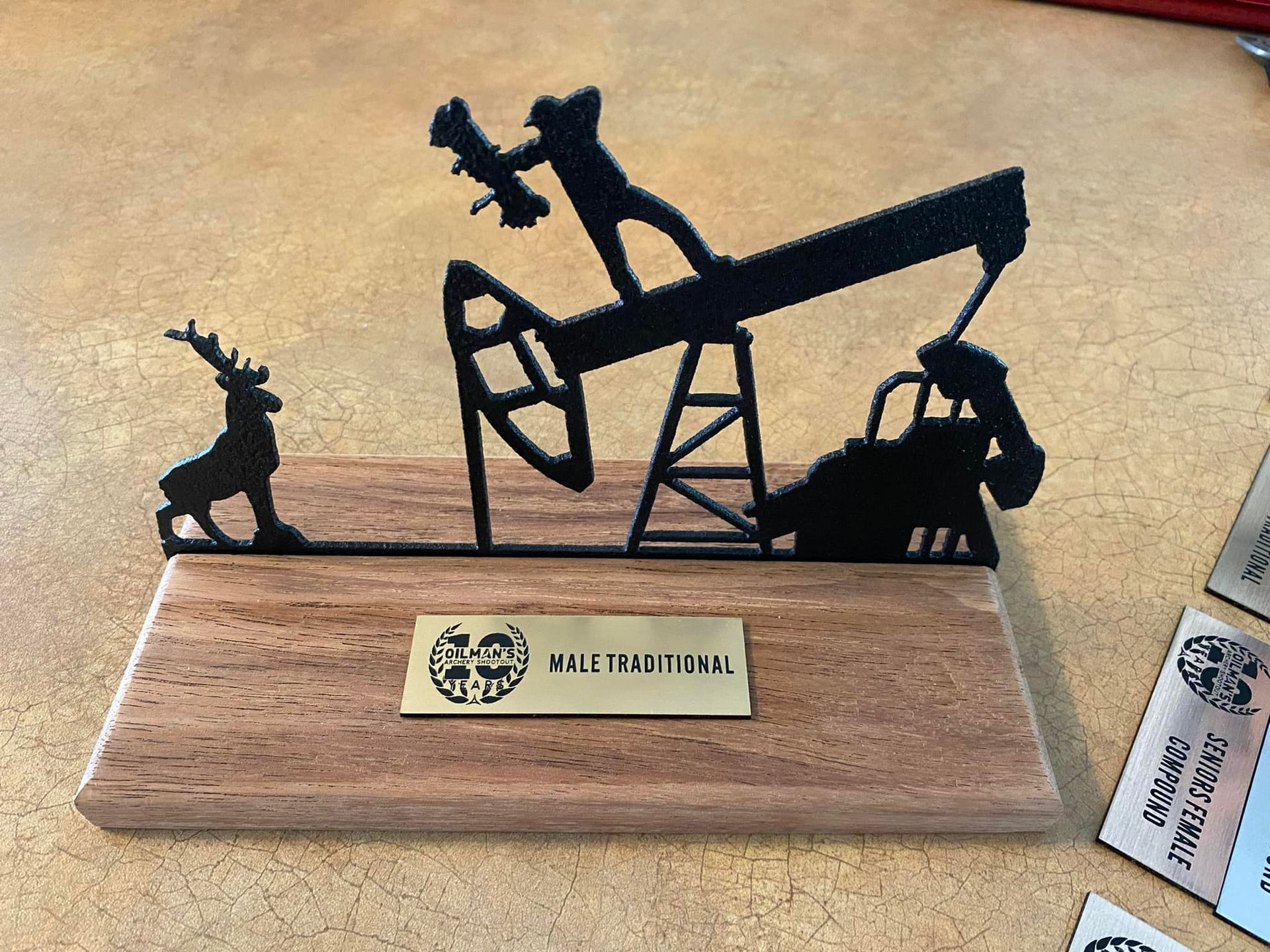 A wooden plaque with a silhouette of an oil pump on it