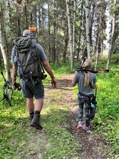 A man and a girl are walking down a path in the woods.