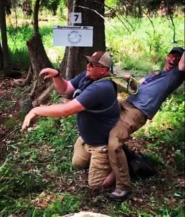 Two men are playing frisbee in the woods near a sign that says 7