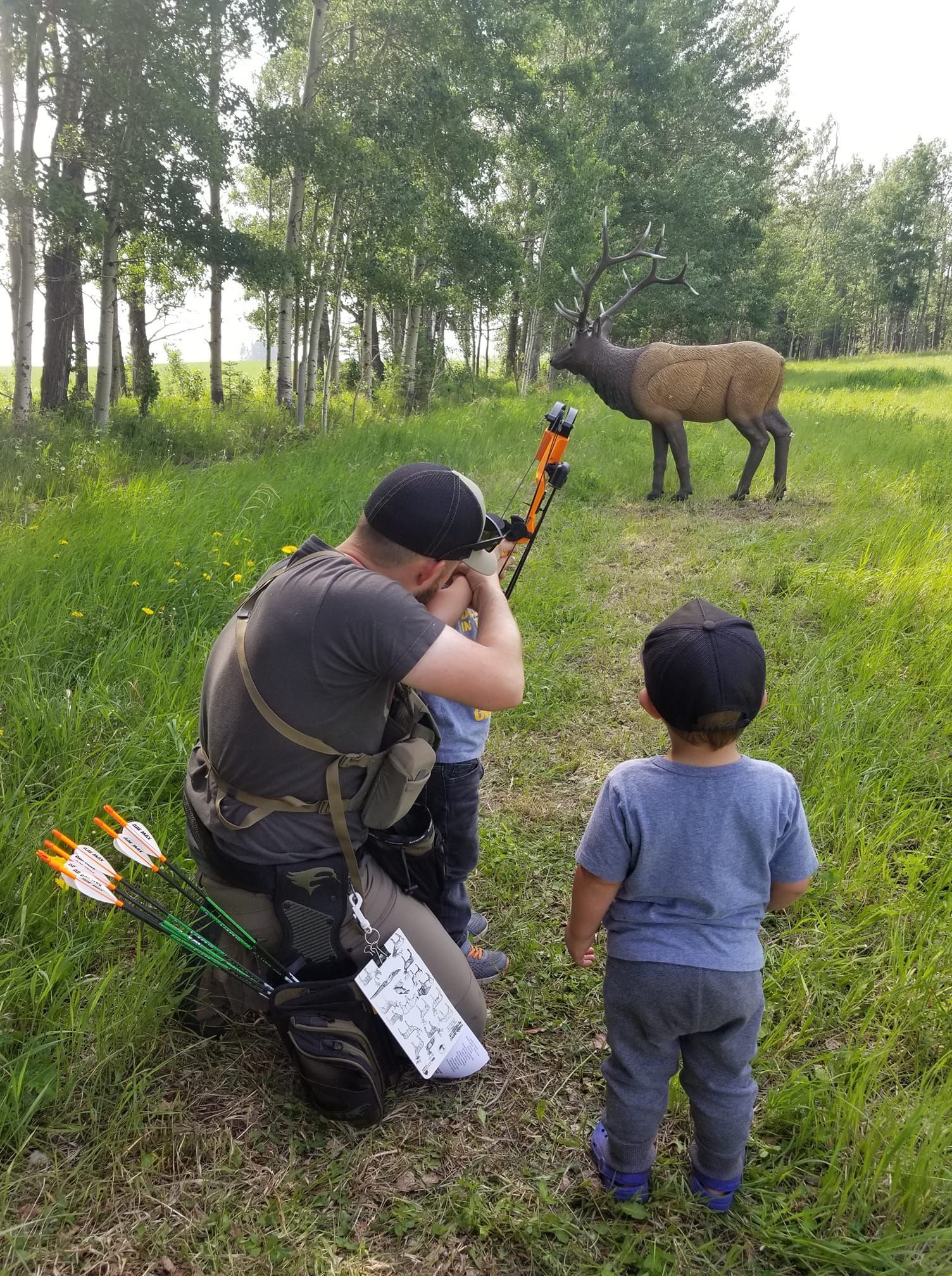A man and a child are looking at a deer in a field.