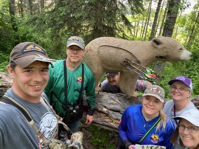 A group of people are posing for a picture in front of a bear statue.