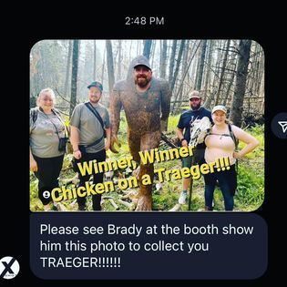 A group of people standing next to a chicken on a traeger