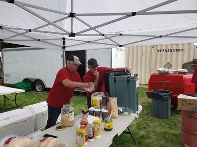A group of men are standing around a table under a tent.