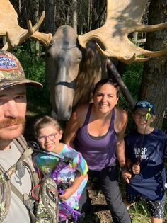 A family is posing for a picture in front of a moose statue.