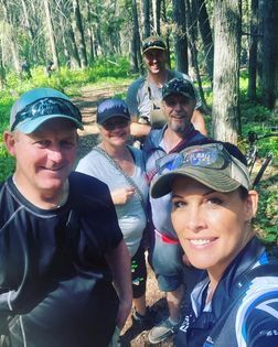 A group of people are posing for a picture in the woods.