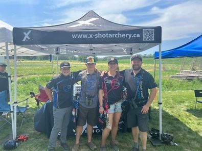 A group of people standing under a tent in a field.