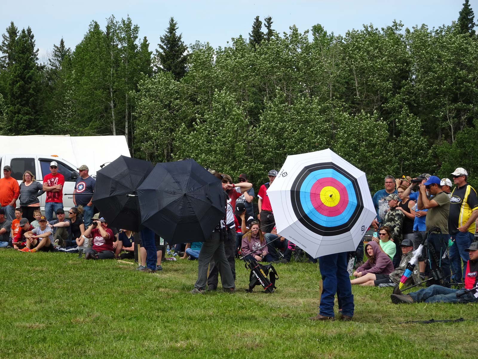 A man is holding an umbrella with a target on it in front of a crowd of people.