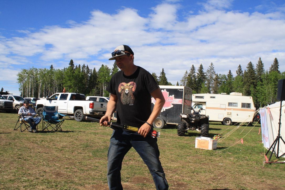 A man in a black shirt with a wolf on it is standing in a field