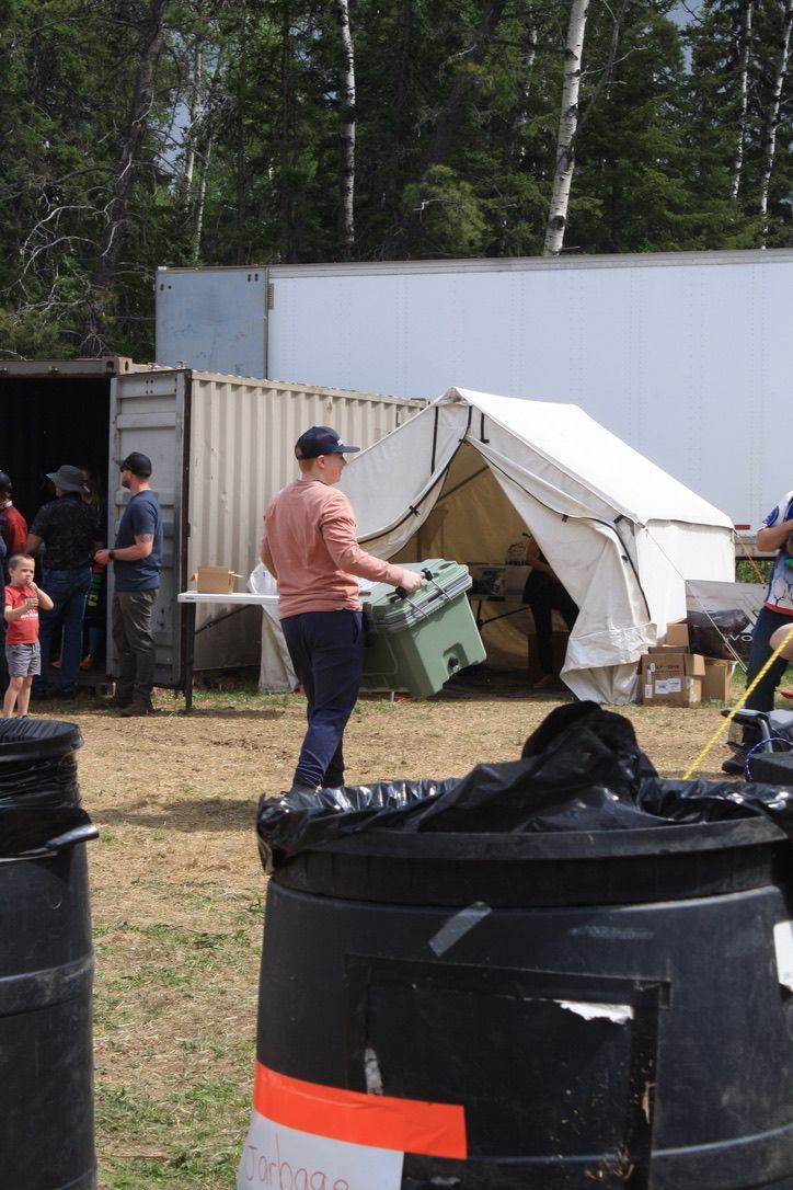 A man is holding a green box in front of a tent