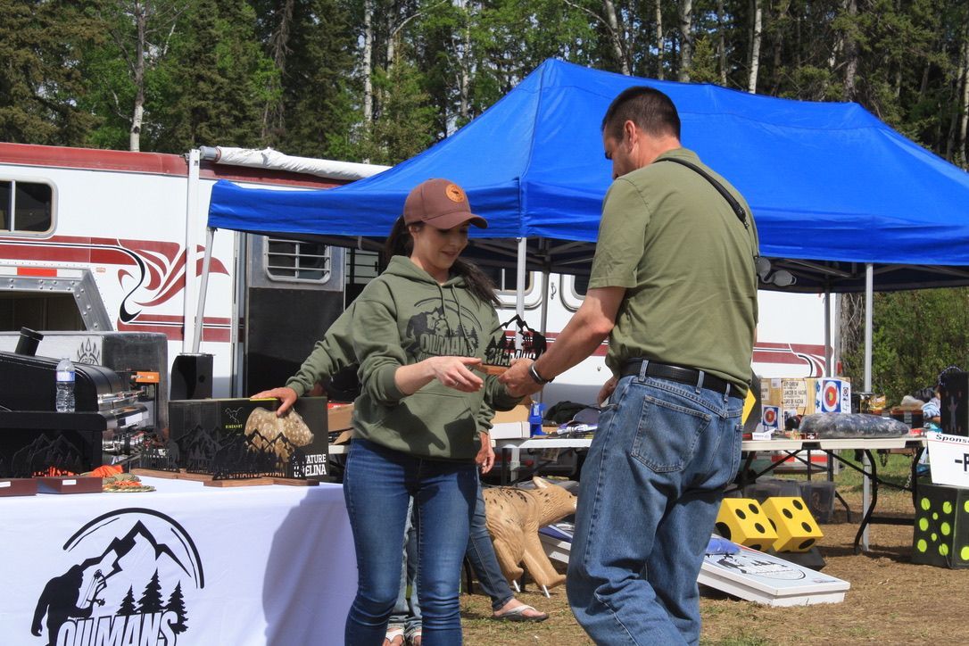 A man and a woman are shaking hands in front of a blue tent