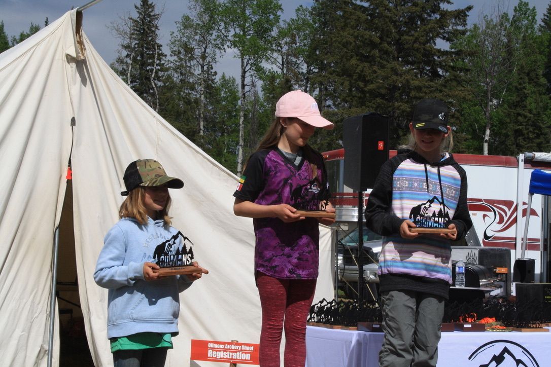A group of people standing in front of a tent holding trophies