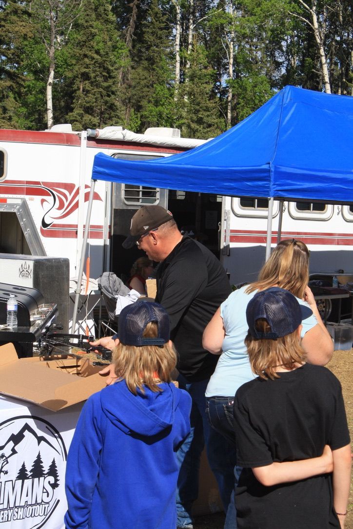 A group of people are standing under a blue tent.