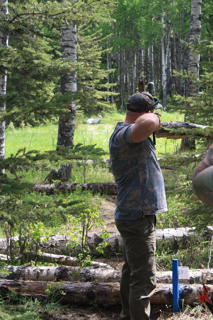 A man is standing in the woods looking through a telescope.