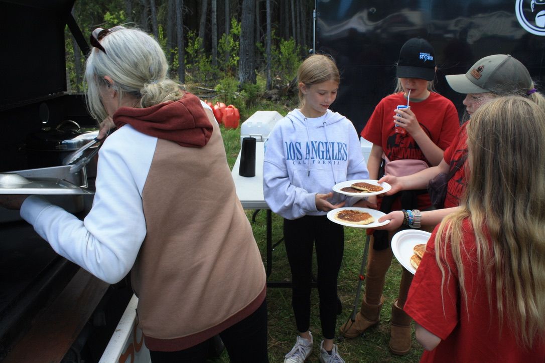 A woman in a los angeles sweatshirt is serving food to a group of people