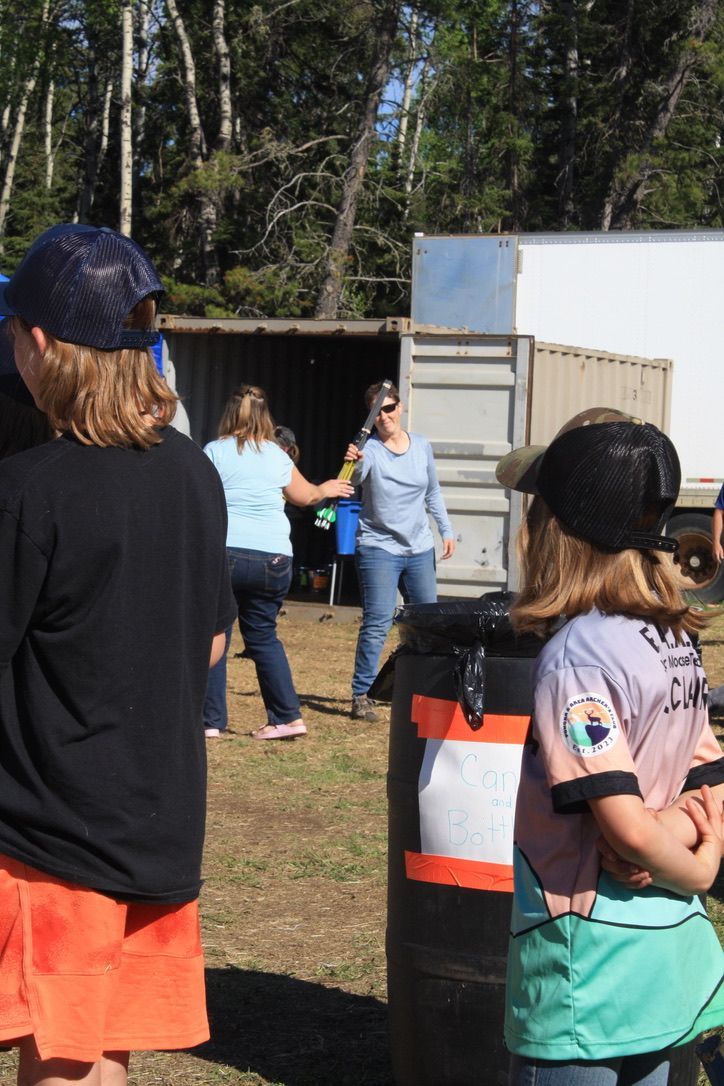 A group of people standing around a barrel in a field