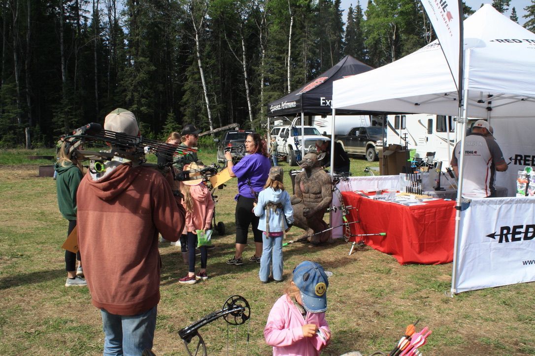 A group of people are standing in a field in front of a tent.