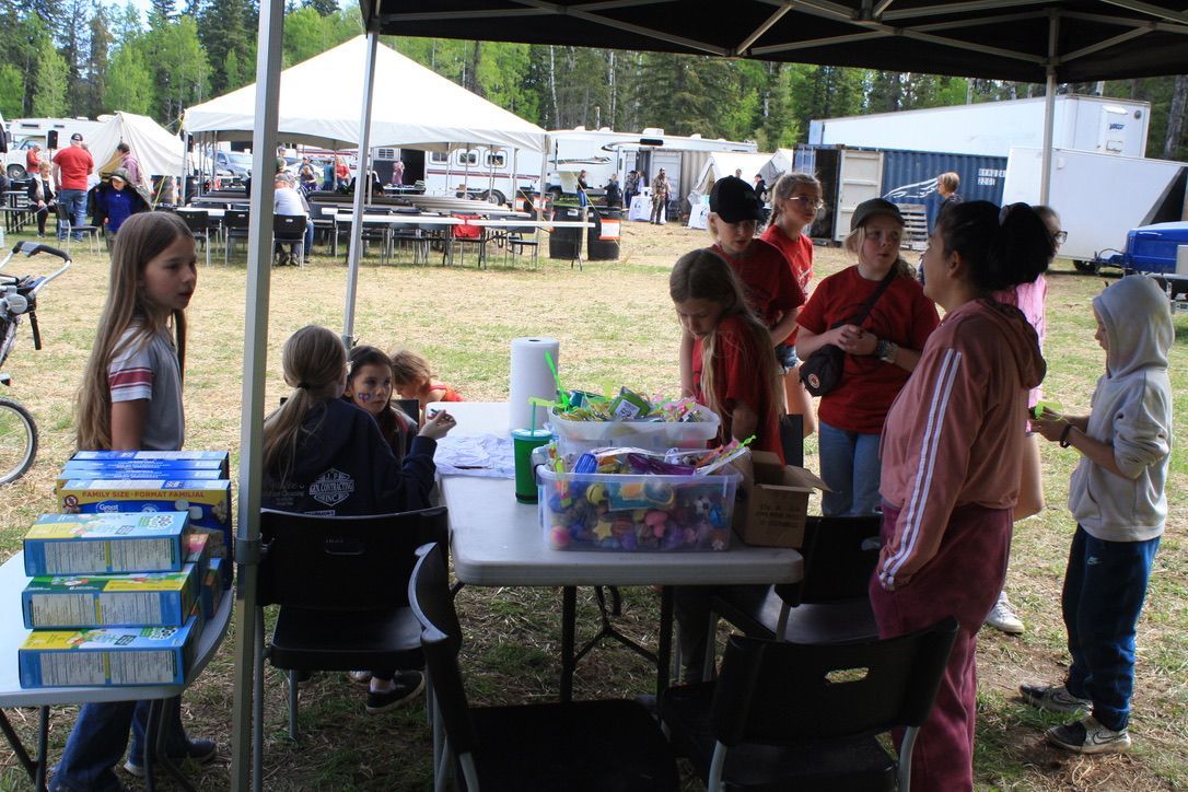 A group of children are standing around a table under a tent.