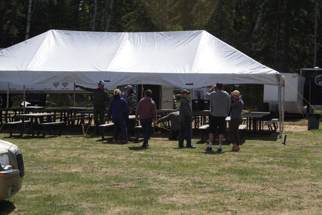 A group of people are standing under a tent in a field.