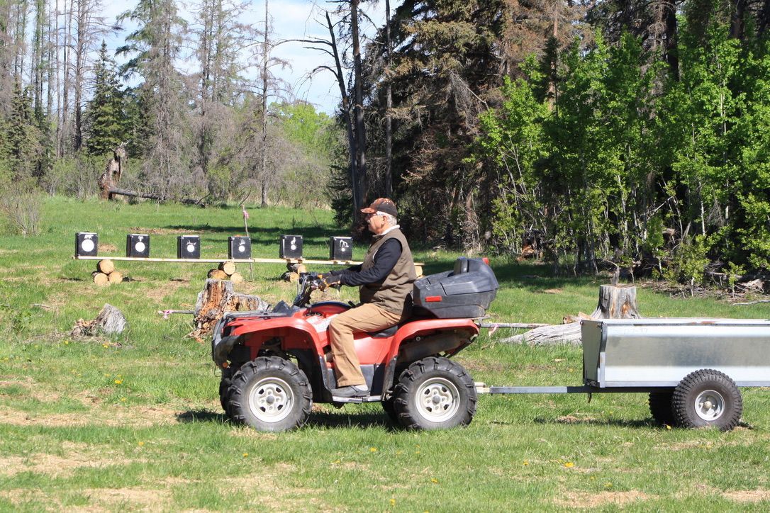 A man is riding an atv with a trailer attached to it.