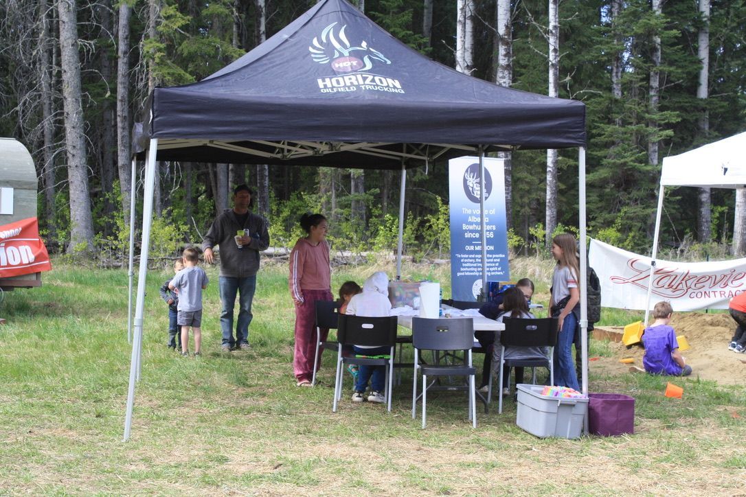 A group of people are standing under a tent in a field.
