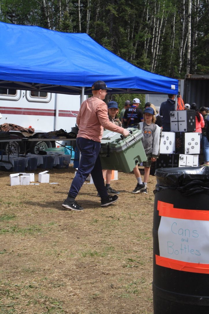 A man is carrying a green cooler in a field.