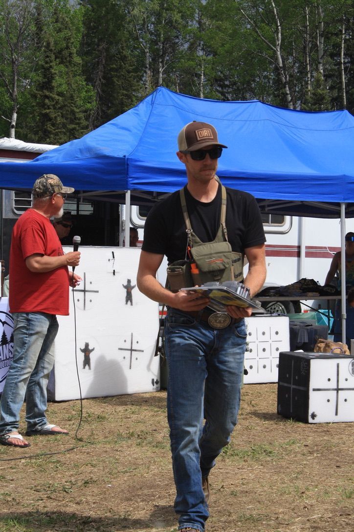 A man is walking in a field with a blue tent in the background