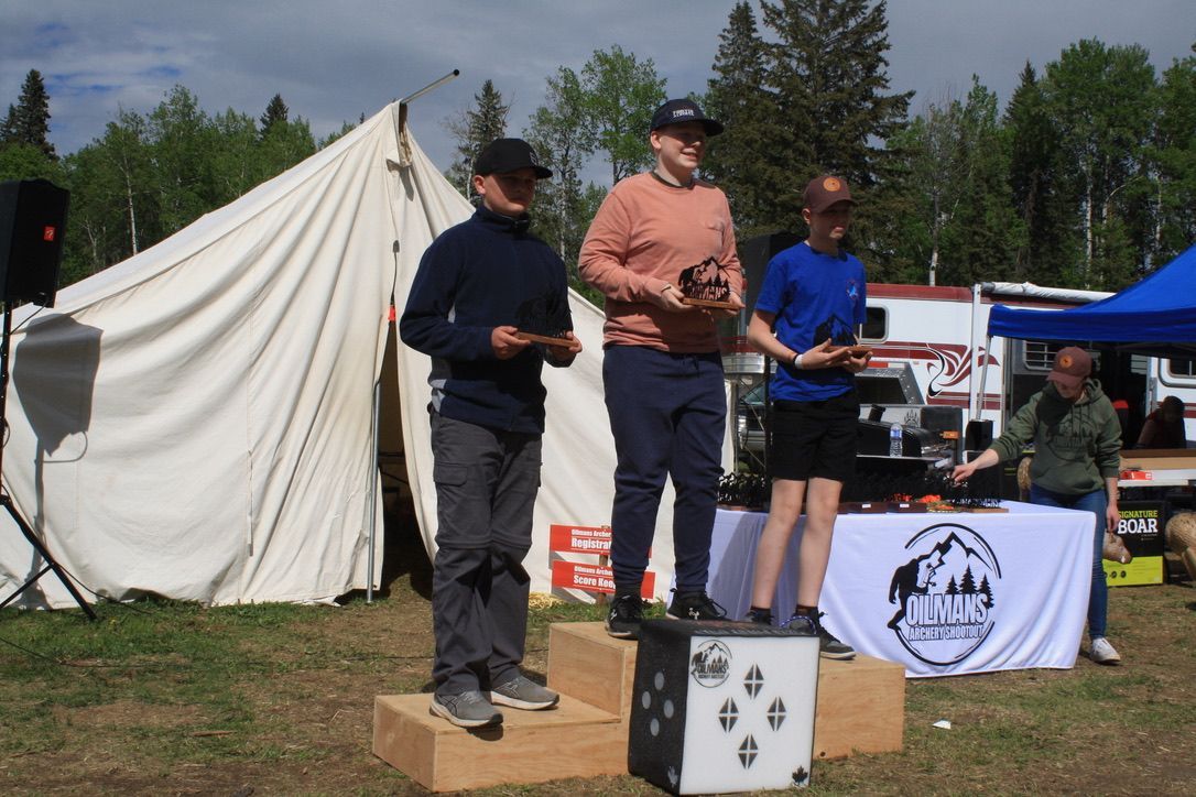 Three men standing on a podium in front of a tent