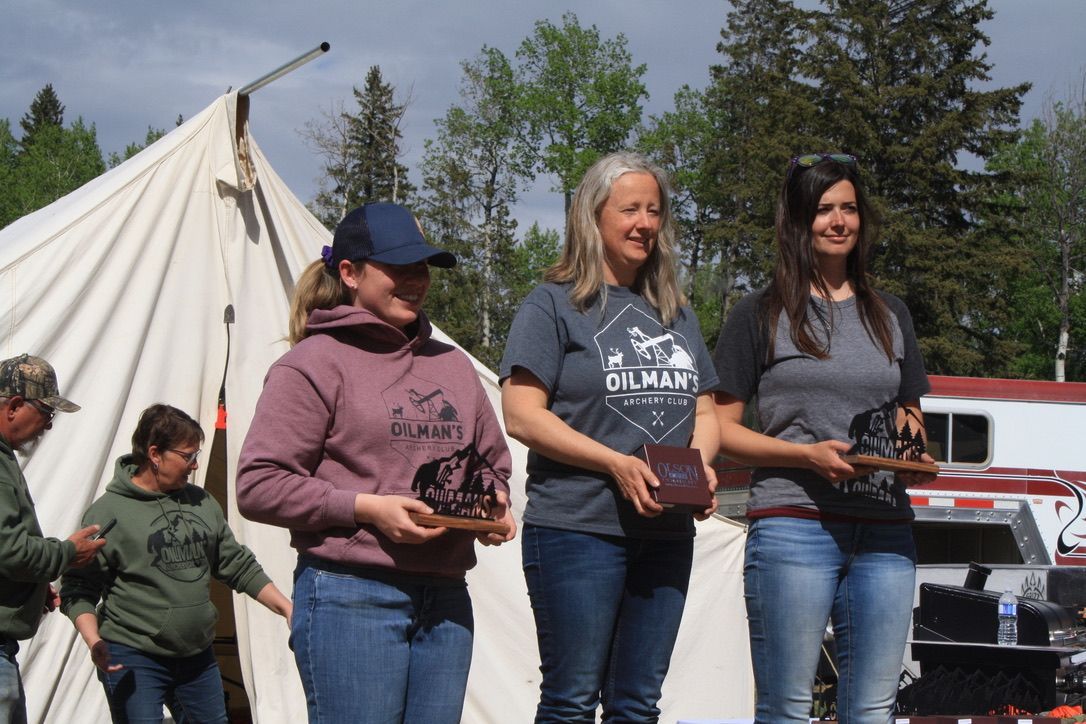 A group of women standing in front of a tent holding plaques.