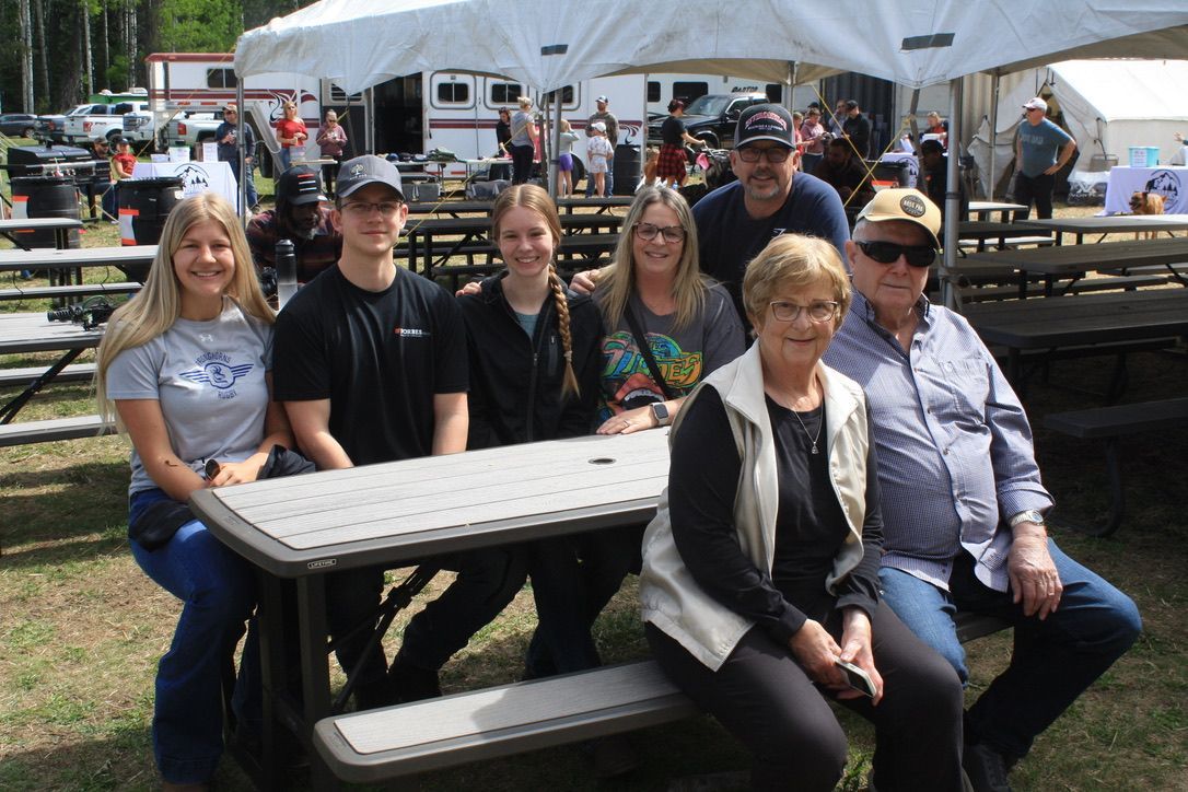 A group of people are posing for a picture at a picnic table